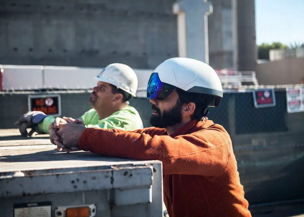 Worker using a smart helmet with hazard alerts.