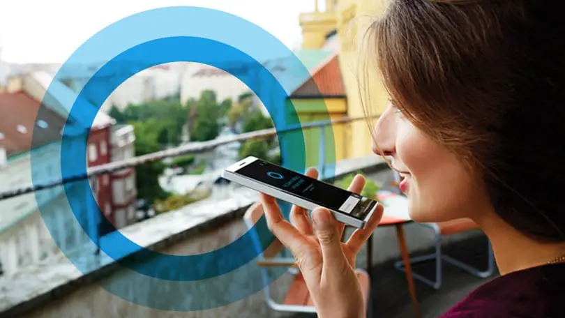 A user speaking into a smartphone using a voice assistant.